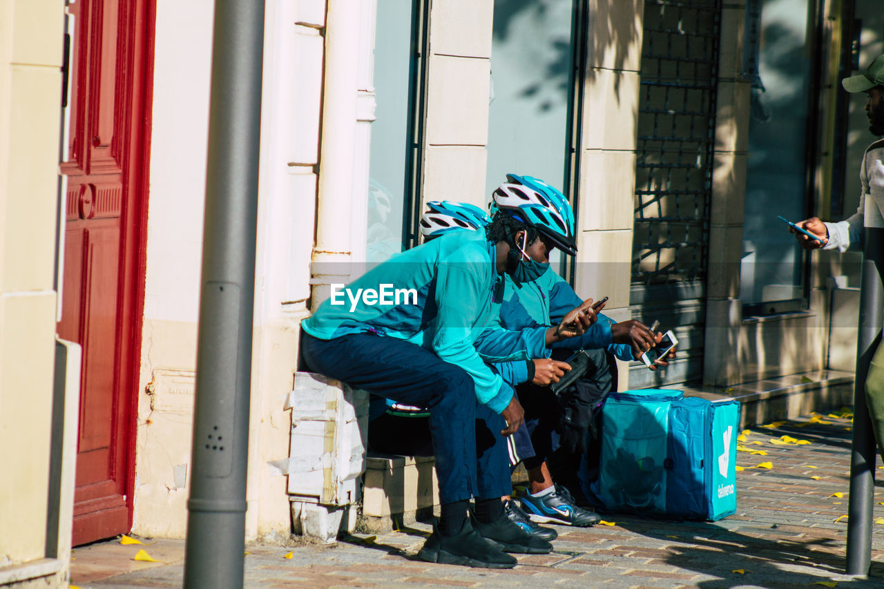 MAN SITTING ON SEAT AGAINST GRAFFITI