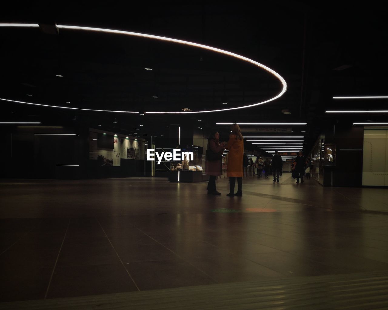 PEOPLE WALKING IN ILLUMINATED UNDERGROUND STATION