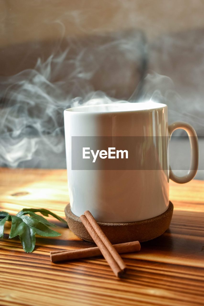 CLOSE-UP OF COFFEE CUP ON TABLE AGAINST WALL