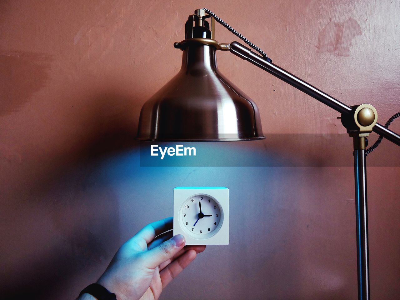 Close-up of cropped hand holding clock