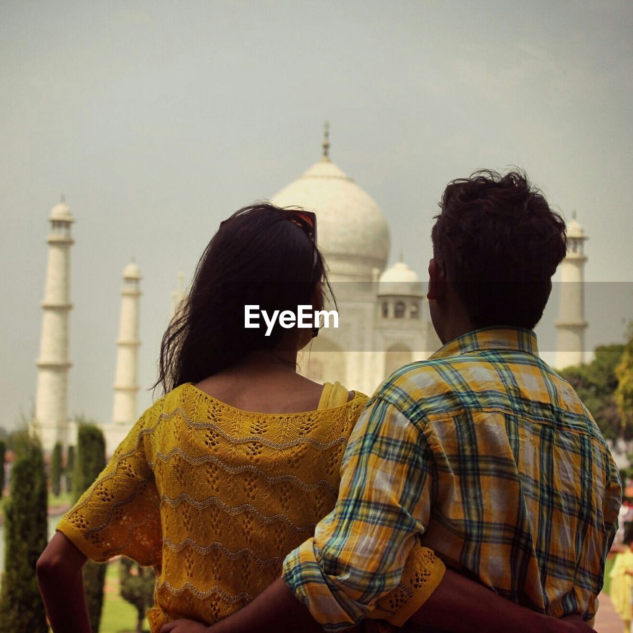 Rear view of couple standing against taj mahal