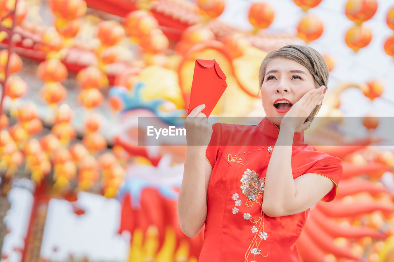 FULL LENGTH OF GIRL STANDING IN RED TRADITIONAL CLOTHING