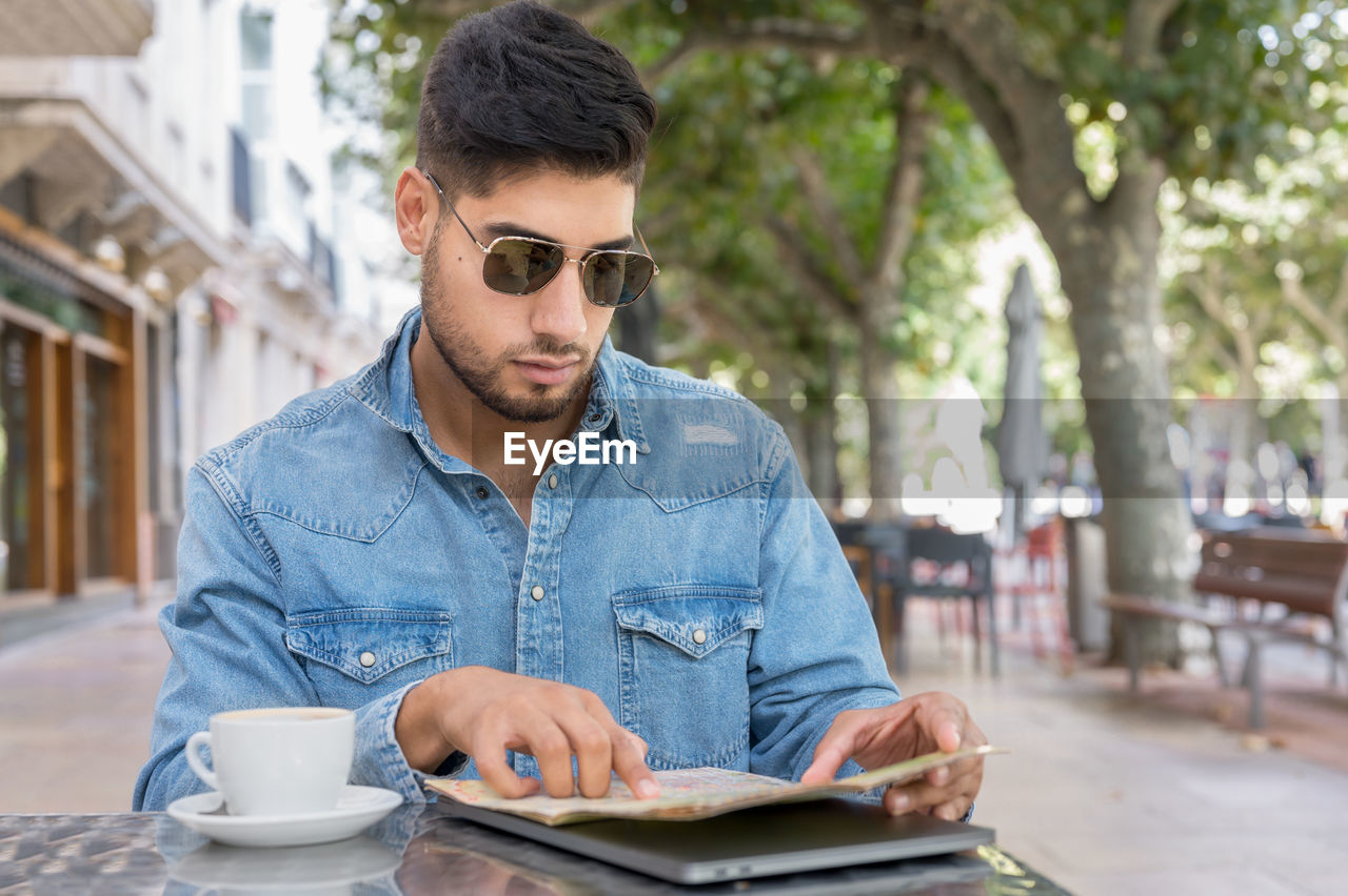 YOUNG MAN WEARING SUNGLASSES AT CAFE