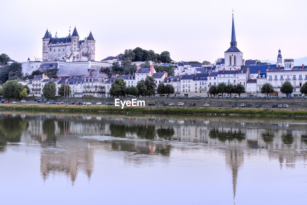 Views of the city of saumur from the riverbank at dusk, with the castle in the background. 