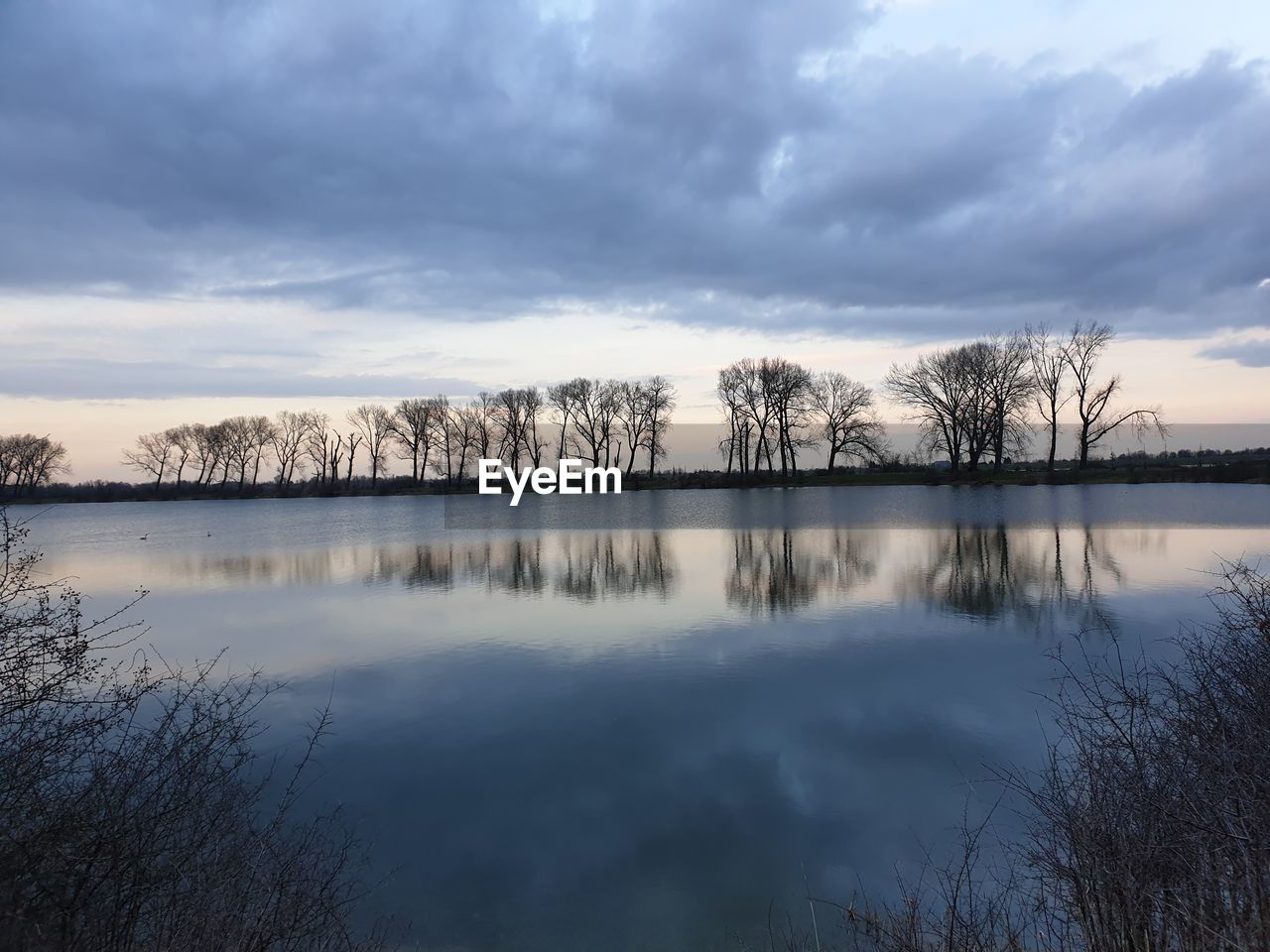 REFLECTION OF TREES IN LAKE AGAINST SKY