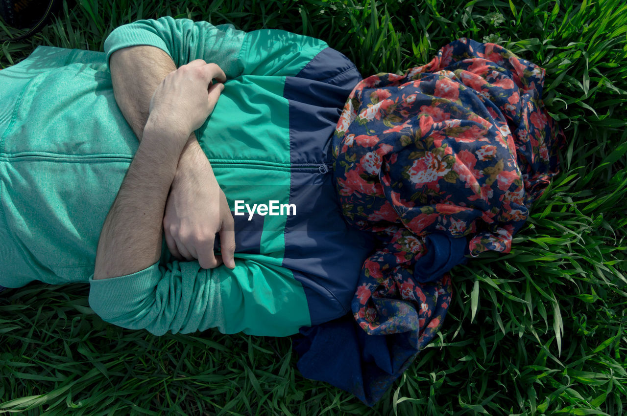 Directly above shot of man with face covered by textile lying on grassy field