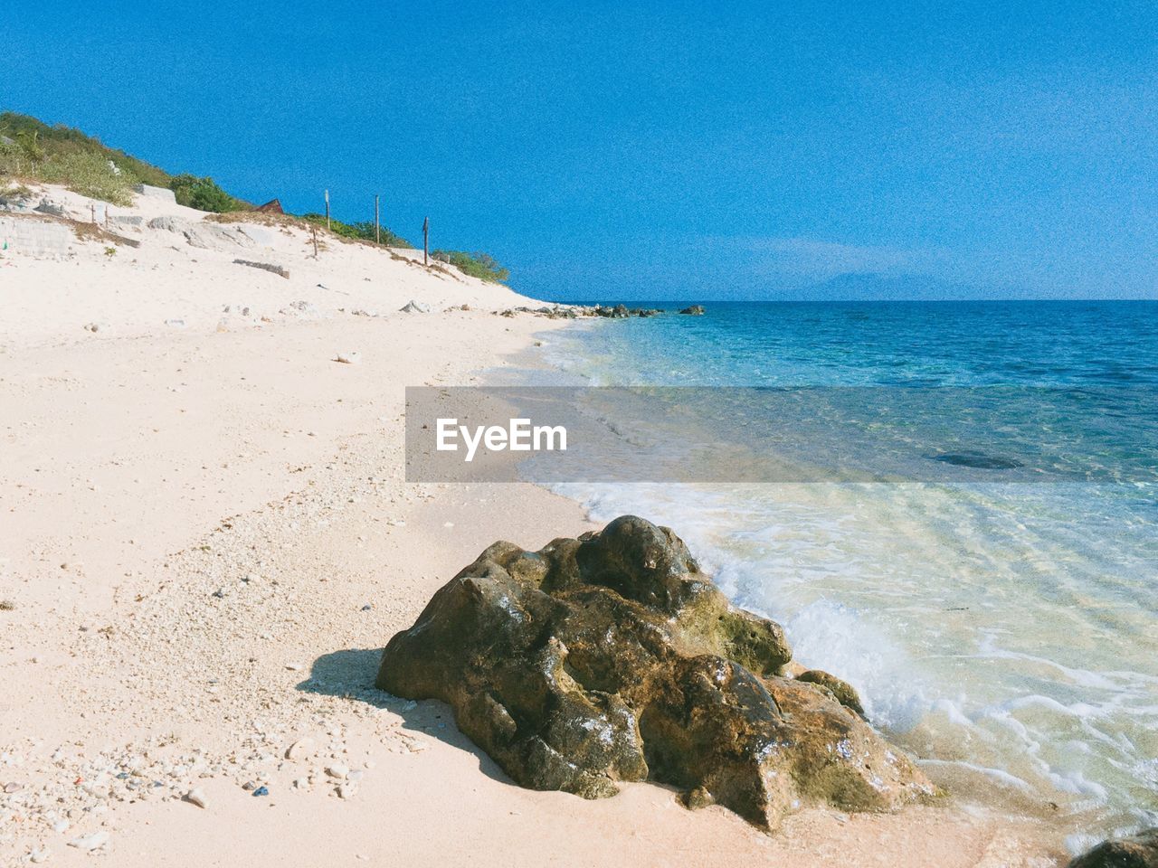 ROCKS ON BEACH AGAINST CLEAR BLUE SKY