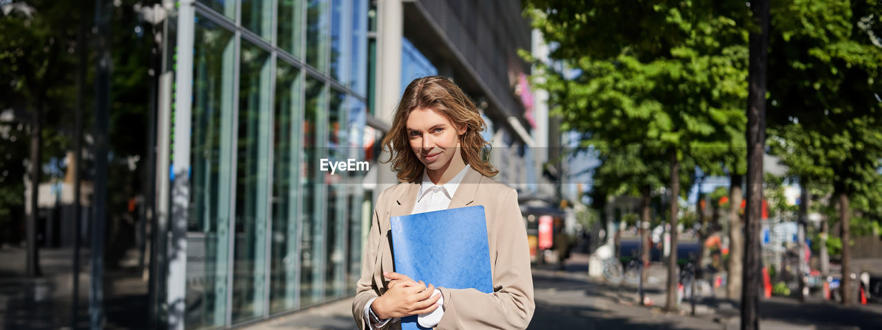 portrait of young woman looking away while standing in city