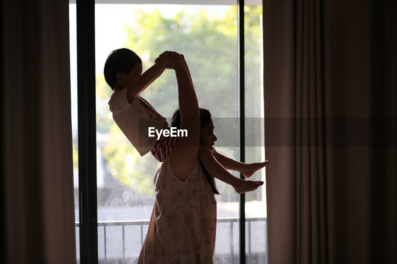 Woman carrying boy on shoulders by window