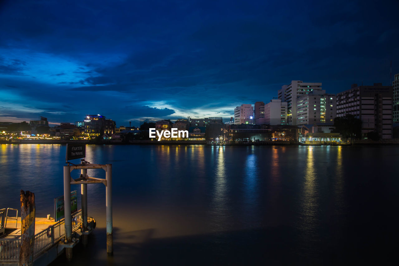 REFLECTION OF ILLUMINATED BUILDINGS IN CALM WATER