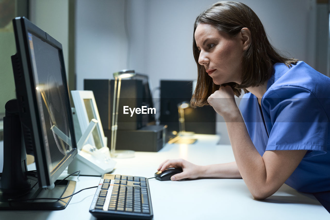 Side view of doctor using computer on desk in office