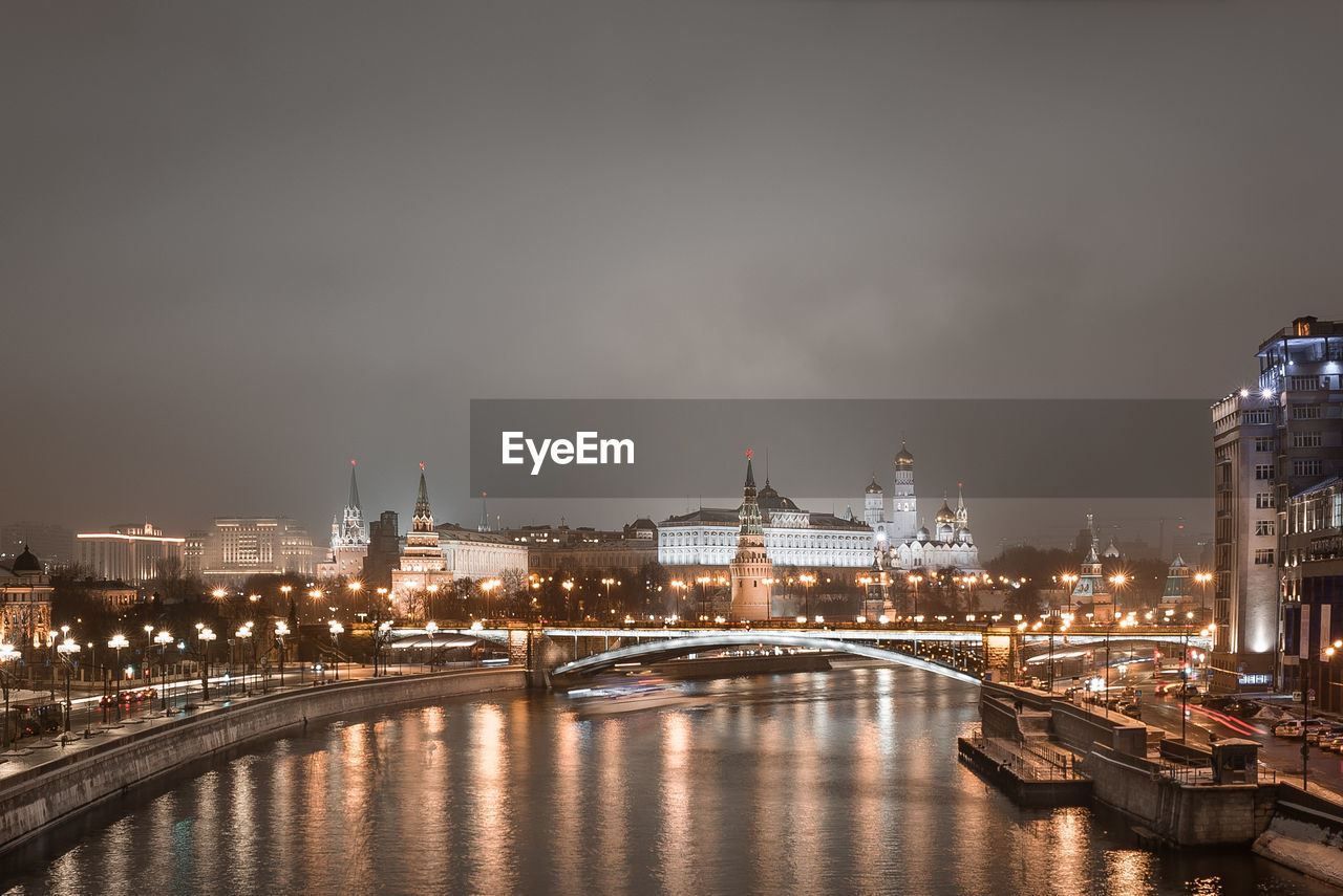 Illuminated bridge over river in city at night