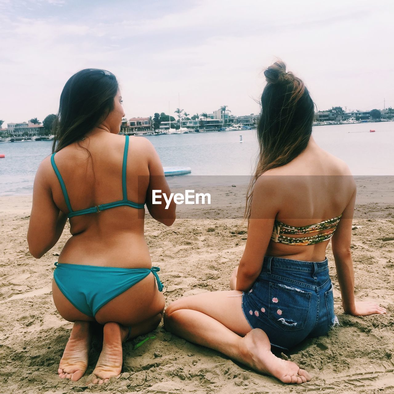 REAR VIEW OF FRIENDS ON BEACH AGAINST SKY