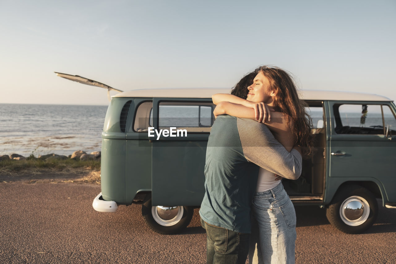 Young couple embracing by sea on road