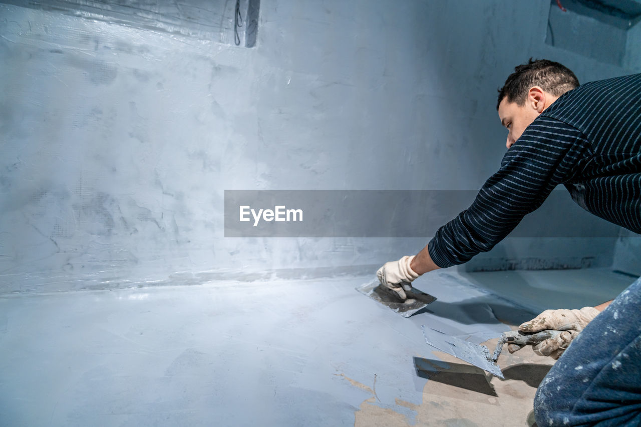 side view of man working on wall