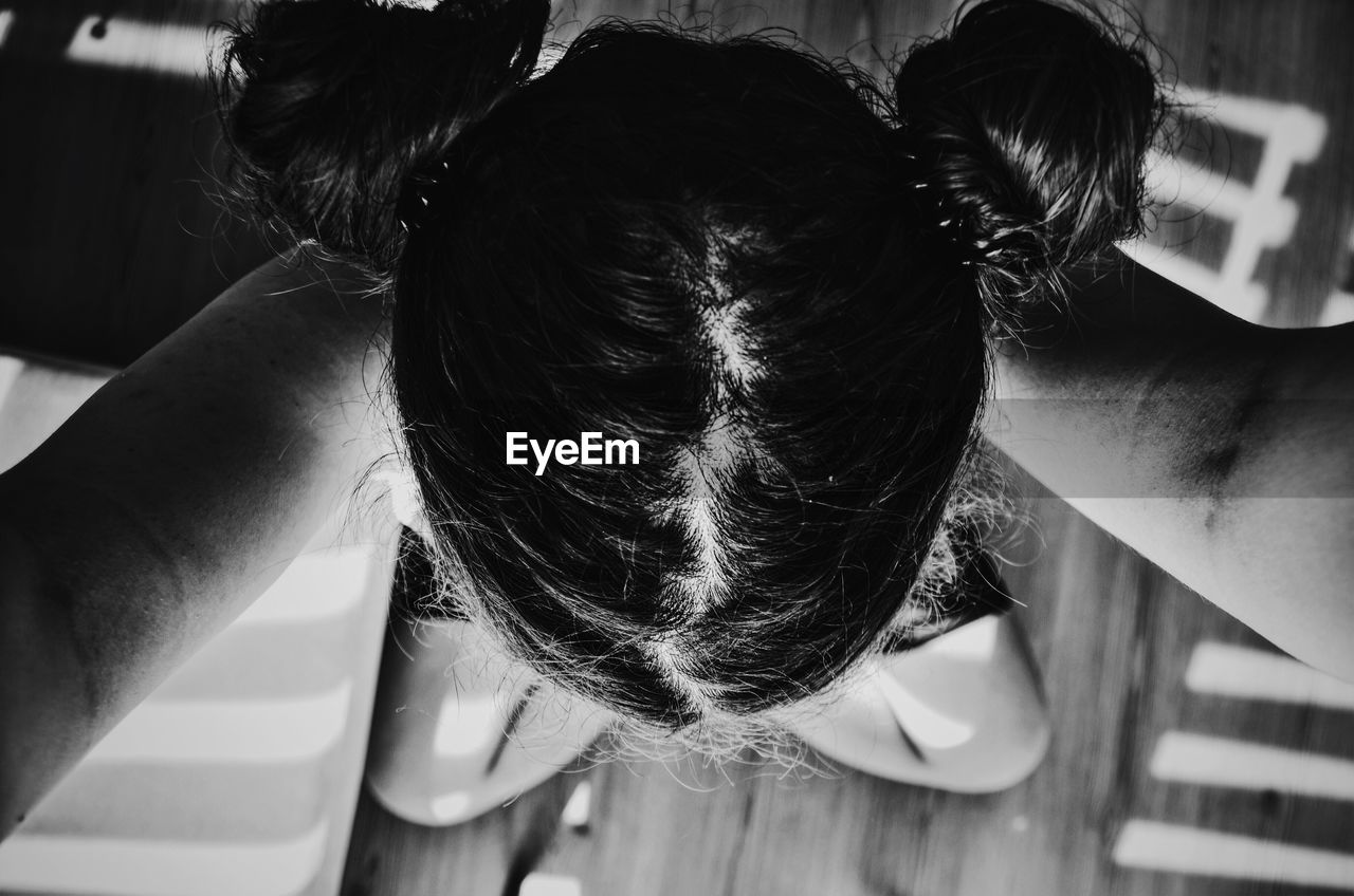 Directly above shot of girl sitting on floorboard at home