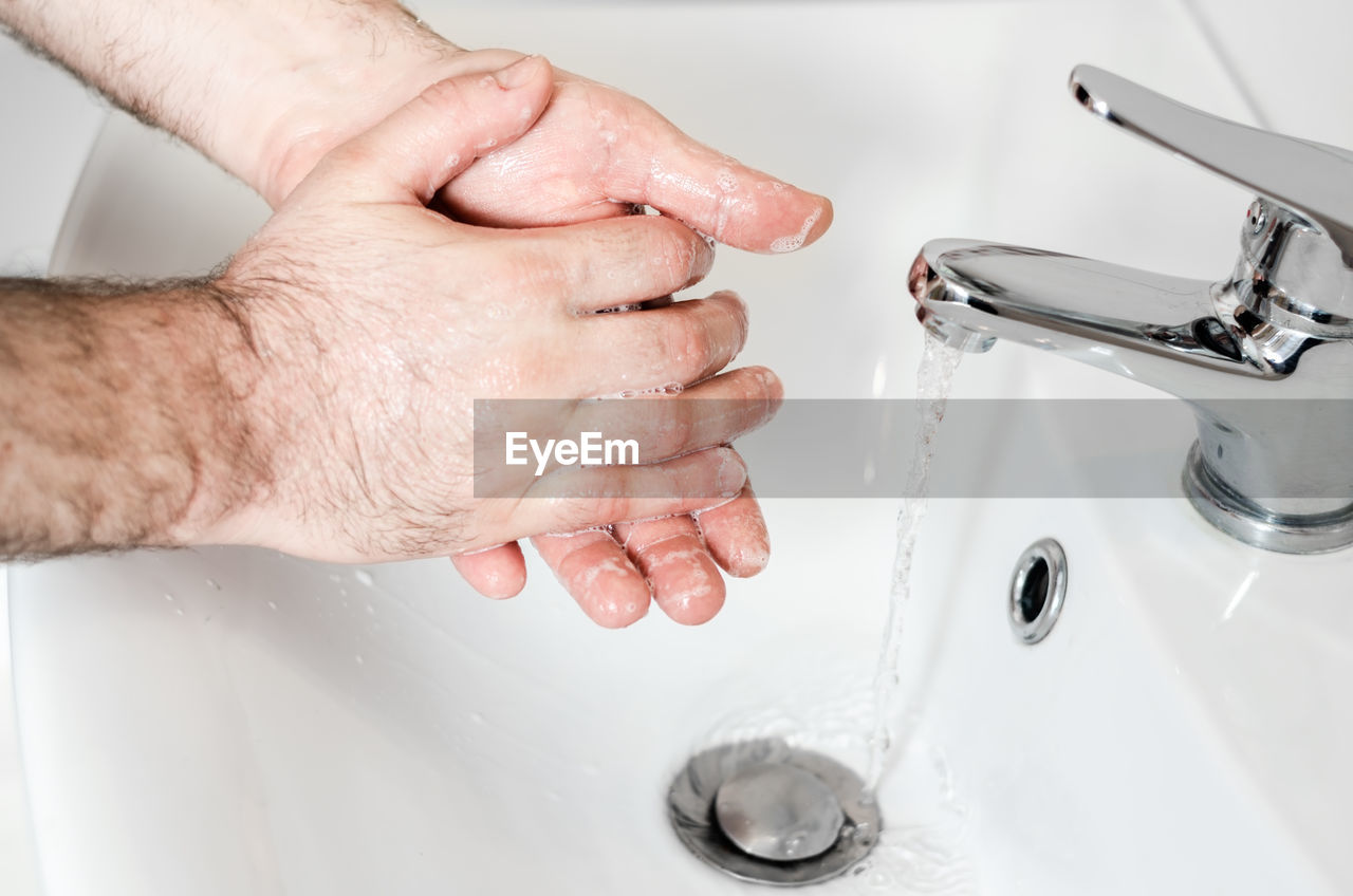 HIGH ANGLE VIEW OF HAND TOUCHING WATER AT HOME