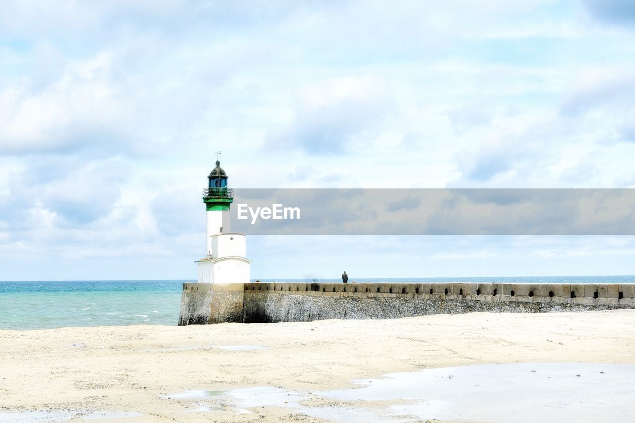 Lighthouse by sea against sky