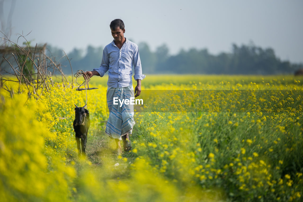 FULL LENGTH OF A WOMAN STANDING IN FIELD