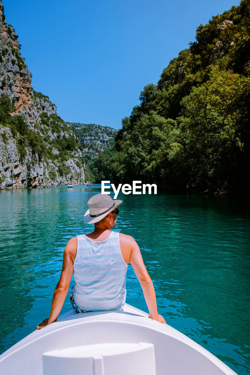 Rear view of man sitting on boat in lake