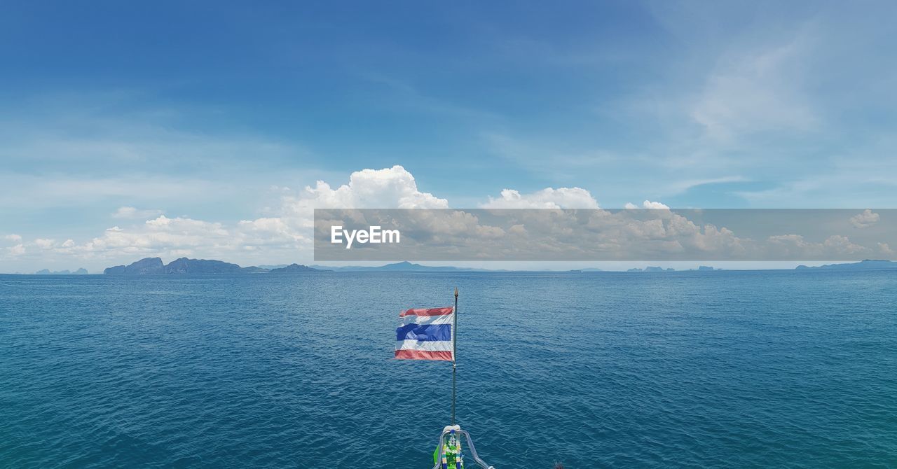 Thai flag with sea in background against blue sky