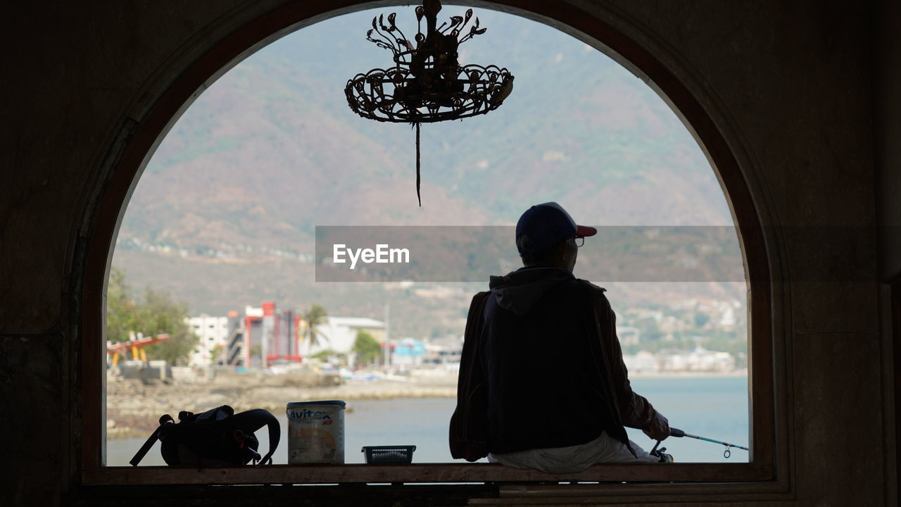 Silhouette of man fishing on window