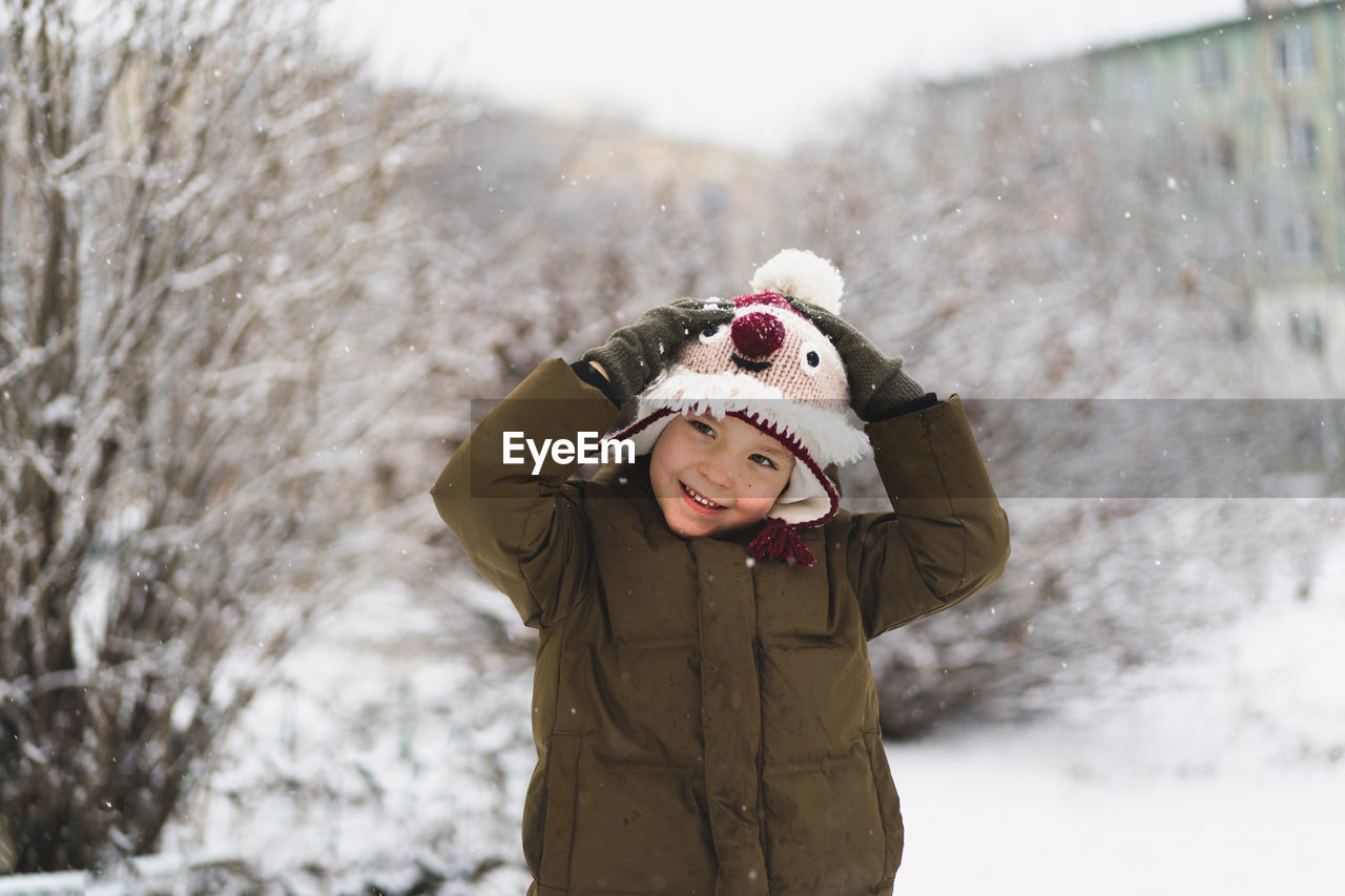 portrait of young woman wearing warm clothing standing outdoors during winter