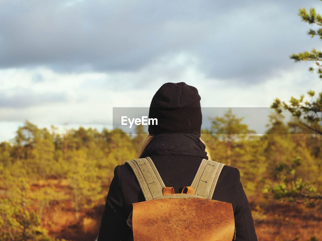 Rear view of woman standing against cloudy sky