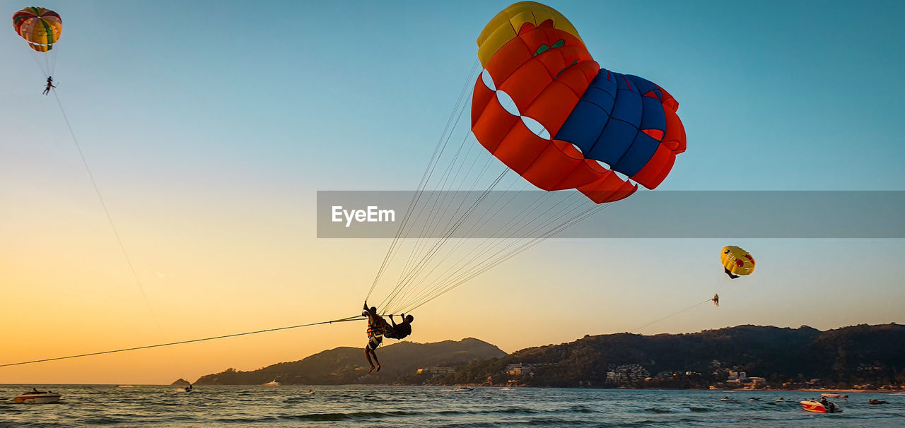 KITE FLYING OVER SEA AGAINST SKY