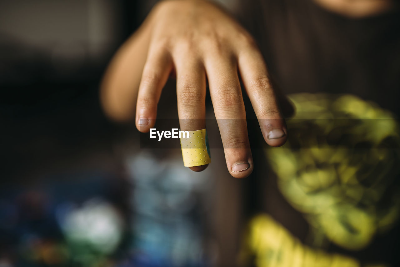 Cropped image of boy showing bandage on finger at home