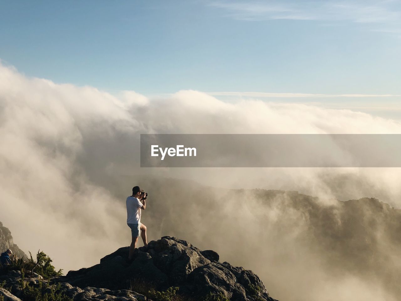 Full length of man photographing landscape against cloudy sky