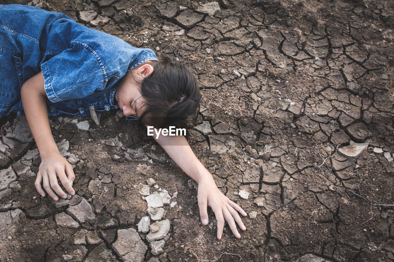 High angle view of girl lying on arid field