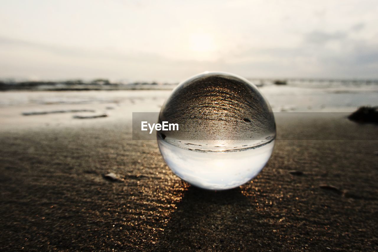 reflection, water, land, sky, light, sand, beach, morning, sea, white, sunlight, close-up, nature, sphere, cloud, macro photography, no people, focus on foreground, blue, single object, tranquility, horizon, outdoors, scenics - nature, crystal ball, rock, ocean, beauty in nature, tranquil scene, horizon over water, black, day