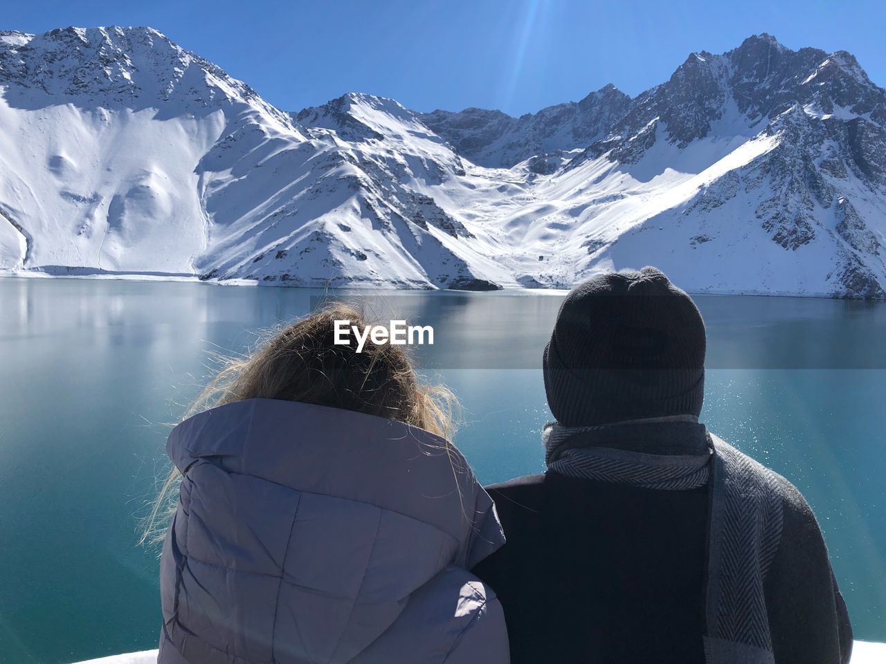 Rear view of friends in warm clothing looking at snowcapped mountains