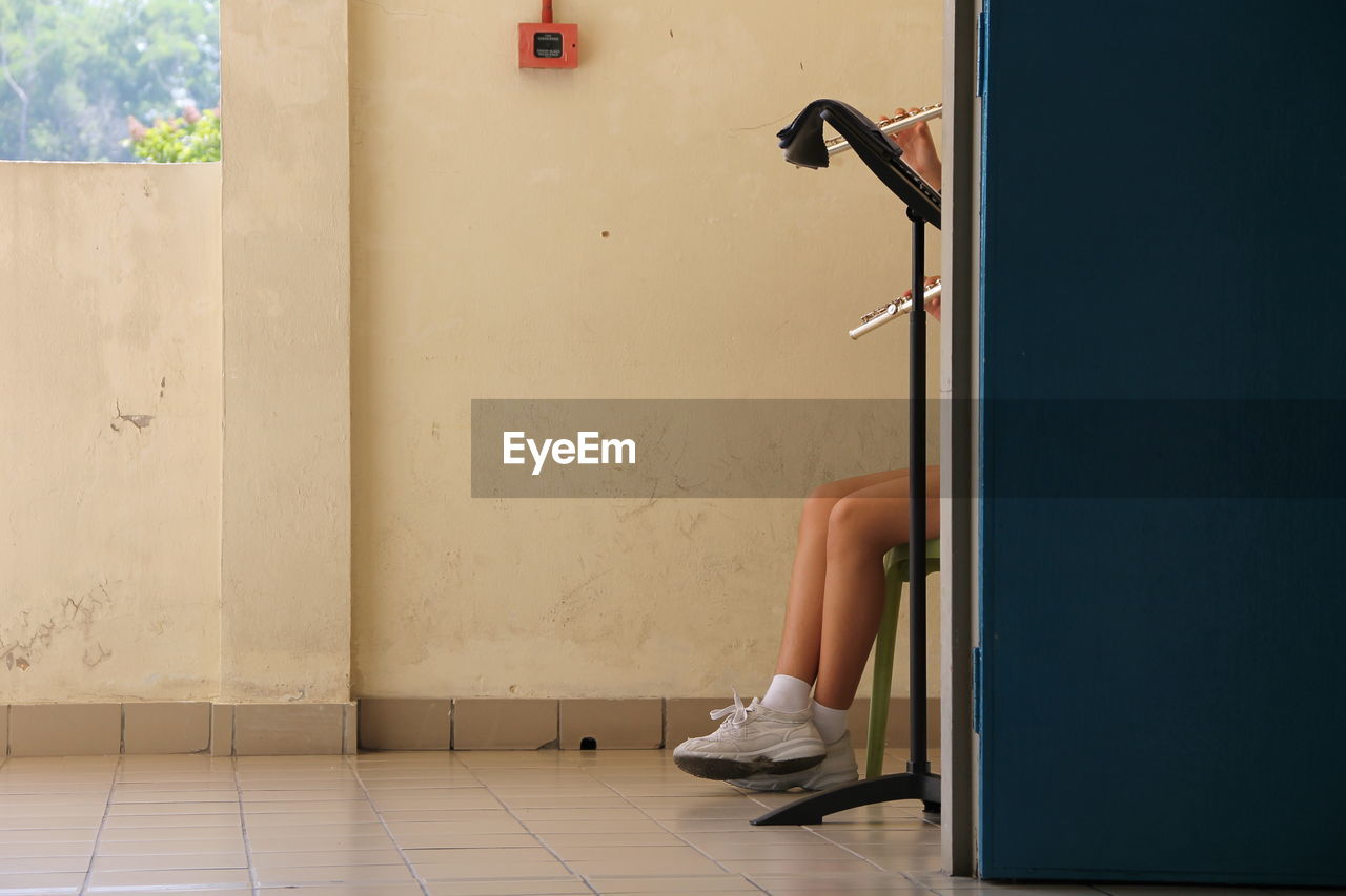 Low section of woman sitting against wall