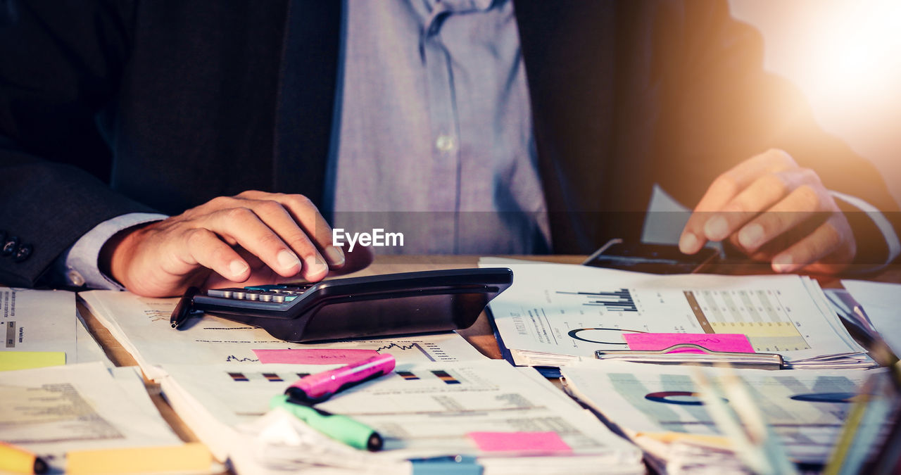 Midsection of businessman working on table