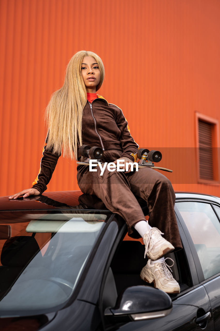 Young african american woman with long blonde hair and sportswear on an orange background