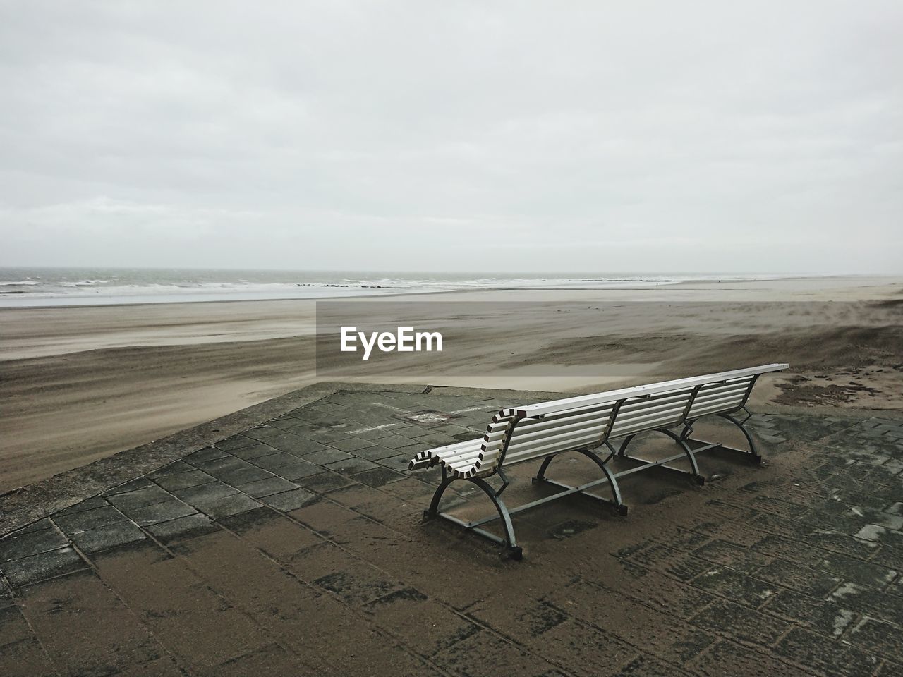EMPTY CHAIR ON SHORE AGAINST SKY