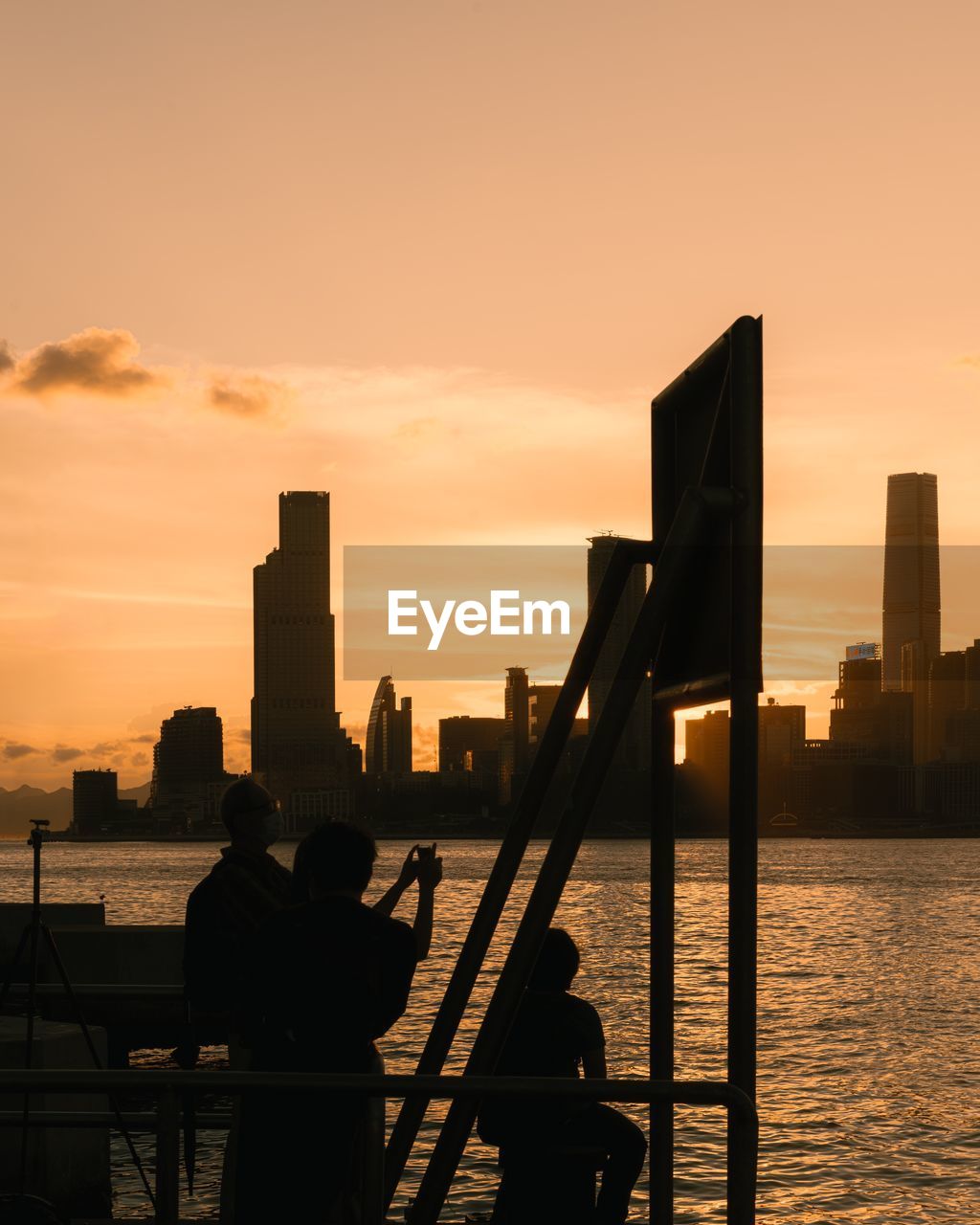 Low angle view of silhouette man standing by sea against clear sky during sunset