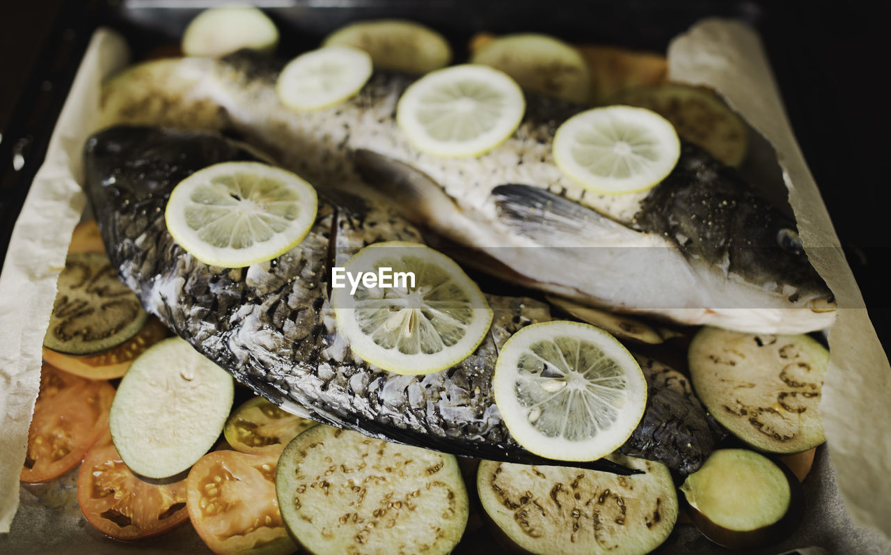 Fish with lemon and vegetables, tomatoes, eggplant on waxed paper, prepared for baking