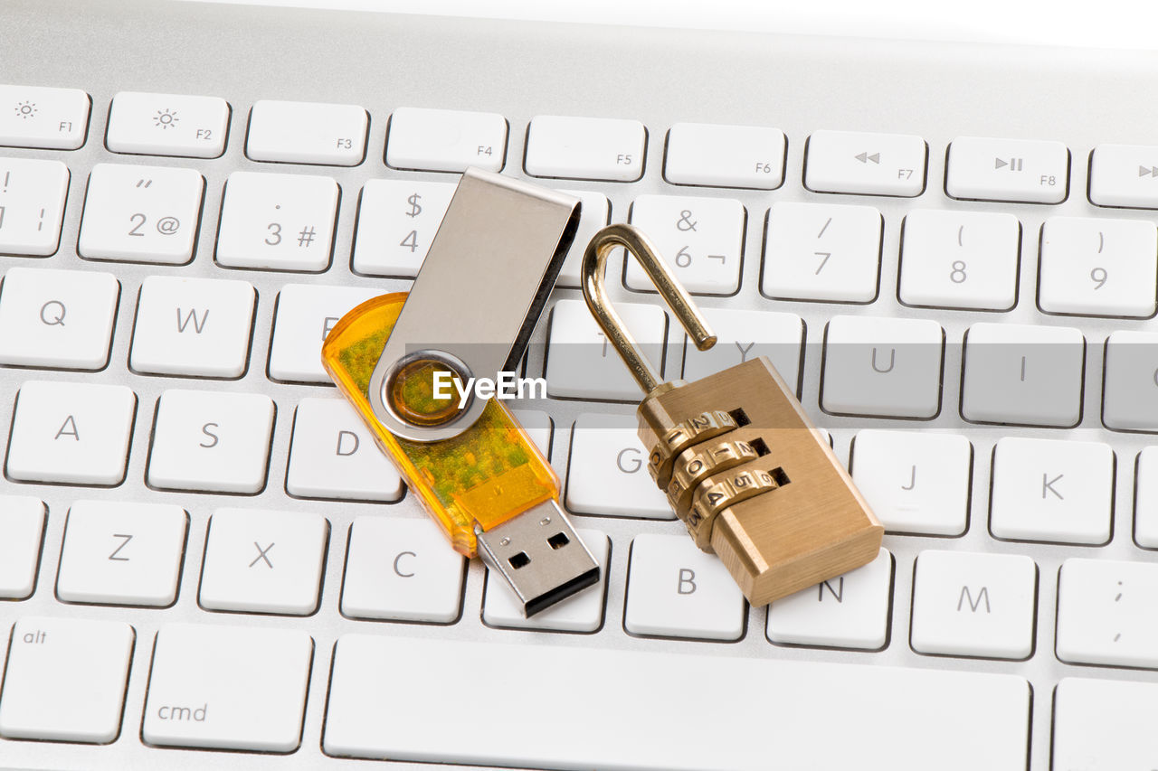 High angle view of padlock and usb stick on computer keyboard against white background