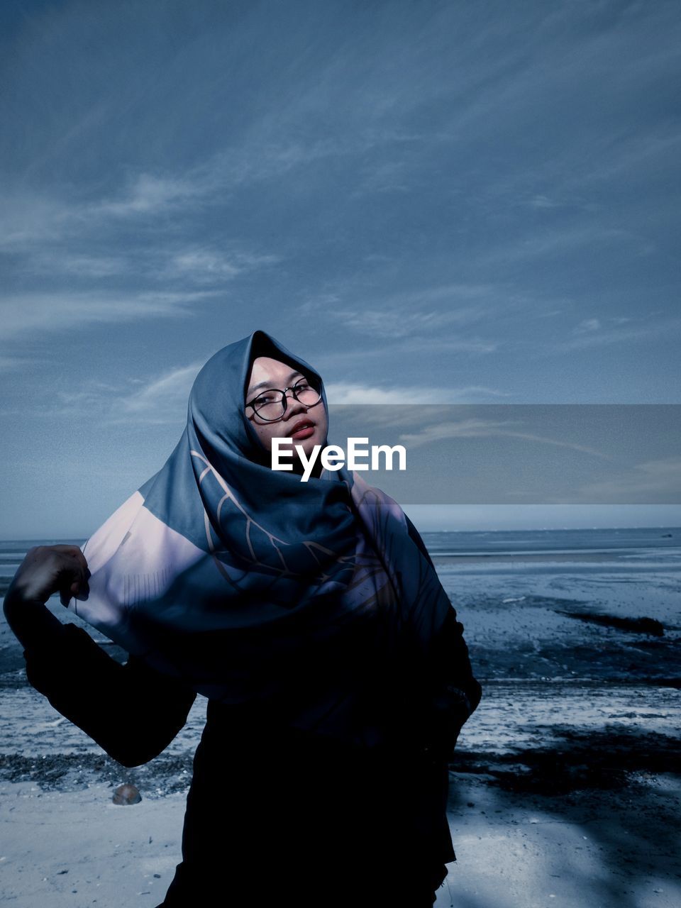 Young woman standing in front of sea against sky