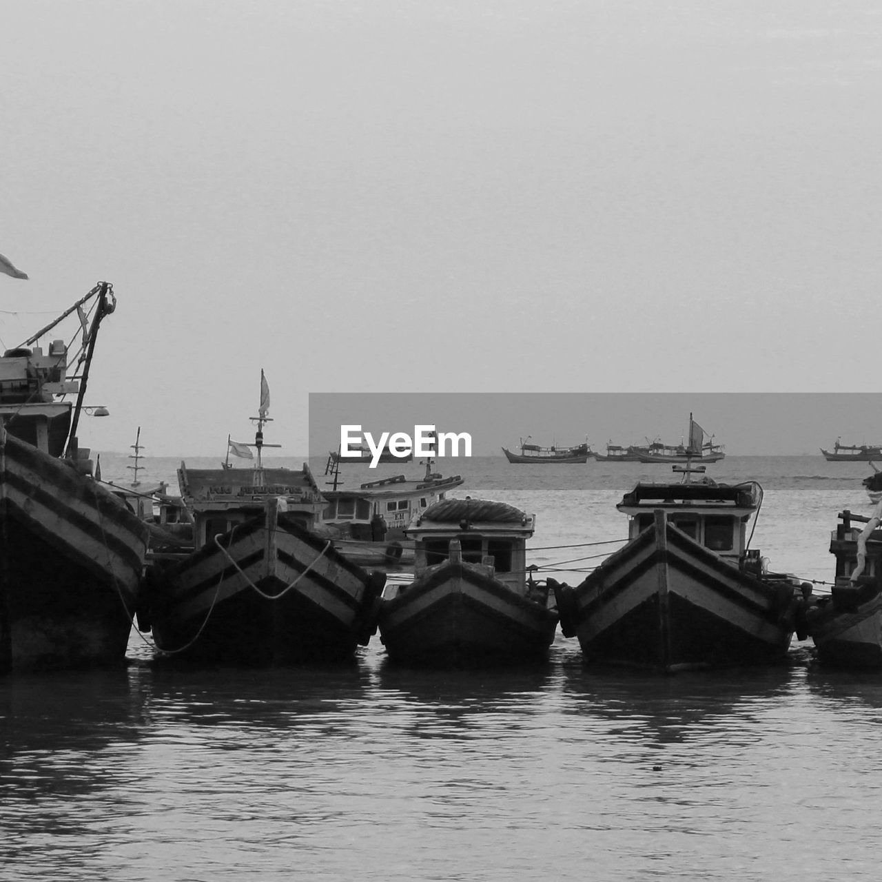 Boats moored in sea against clear sky