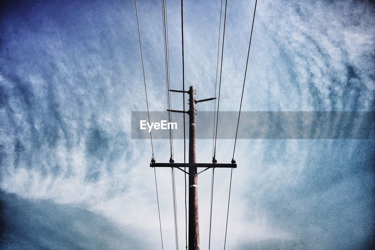 Low angle view of telephone pole against cloudy sky