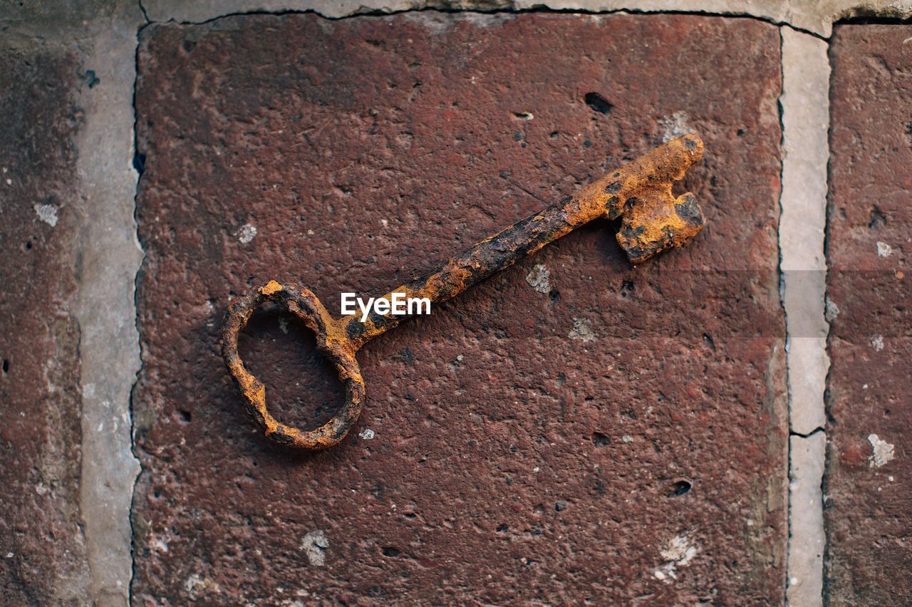 Close-up of rusty key on footpath