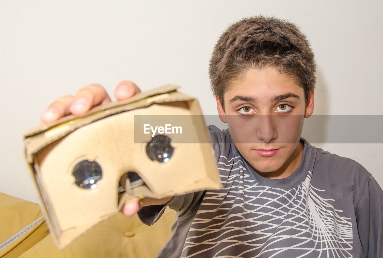 Portrait of boy showing cardboard virtual reality simulator attached to smart phone