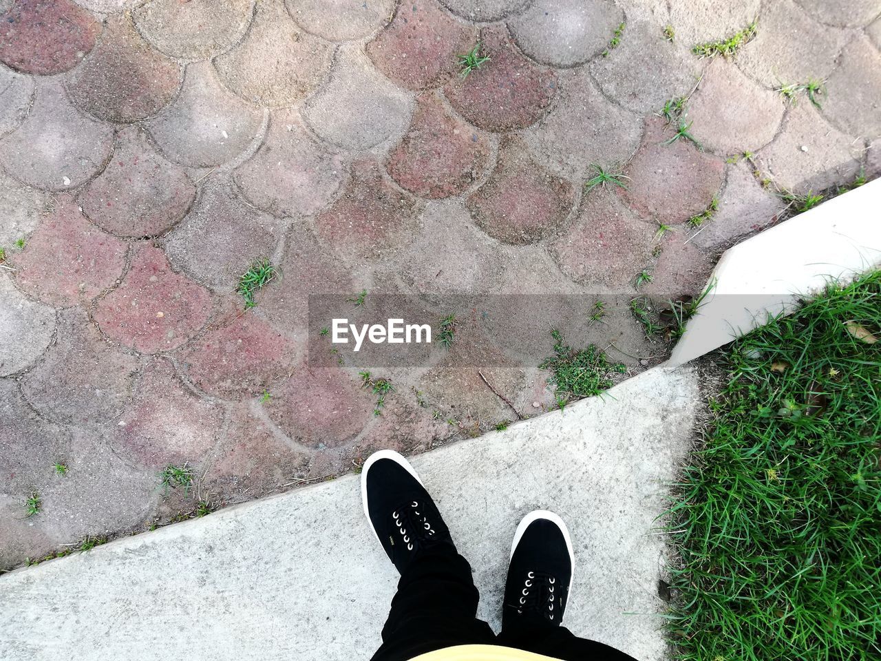 LOW SECTION OF PERSON STANDING ON COBBLESTONE STREET