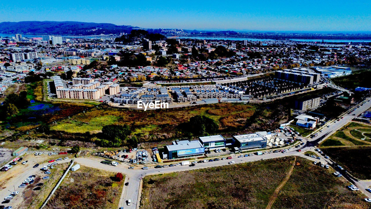 aerial photography, architecture, bird's-eye view, built structure, city, building exterior, high angle view, cityscape, aerial view, nature, building, sport venue, sky, crowd, stadium, transportation, landmark, outdoors, travel destinations, residential district, day, road, landscape, crowded, residential area, travel, blue, sports, metropolitan area, water, arena, street