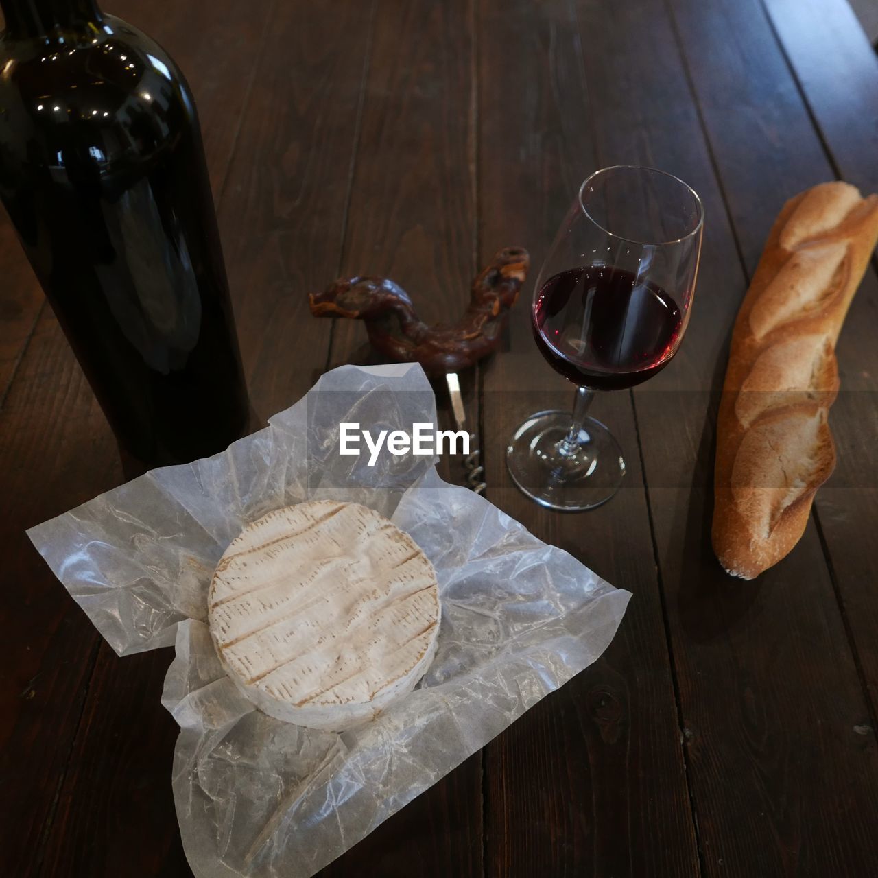 High angle view of camembert and baguette with wine on wooden table