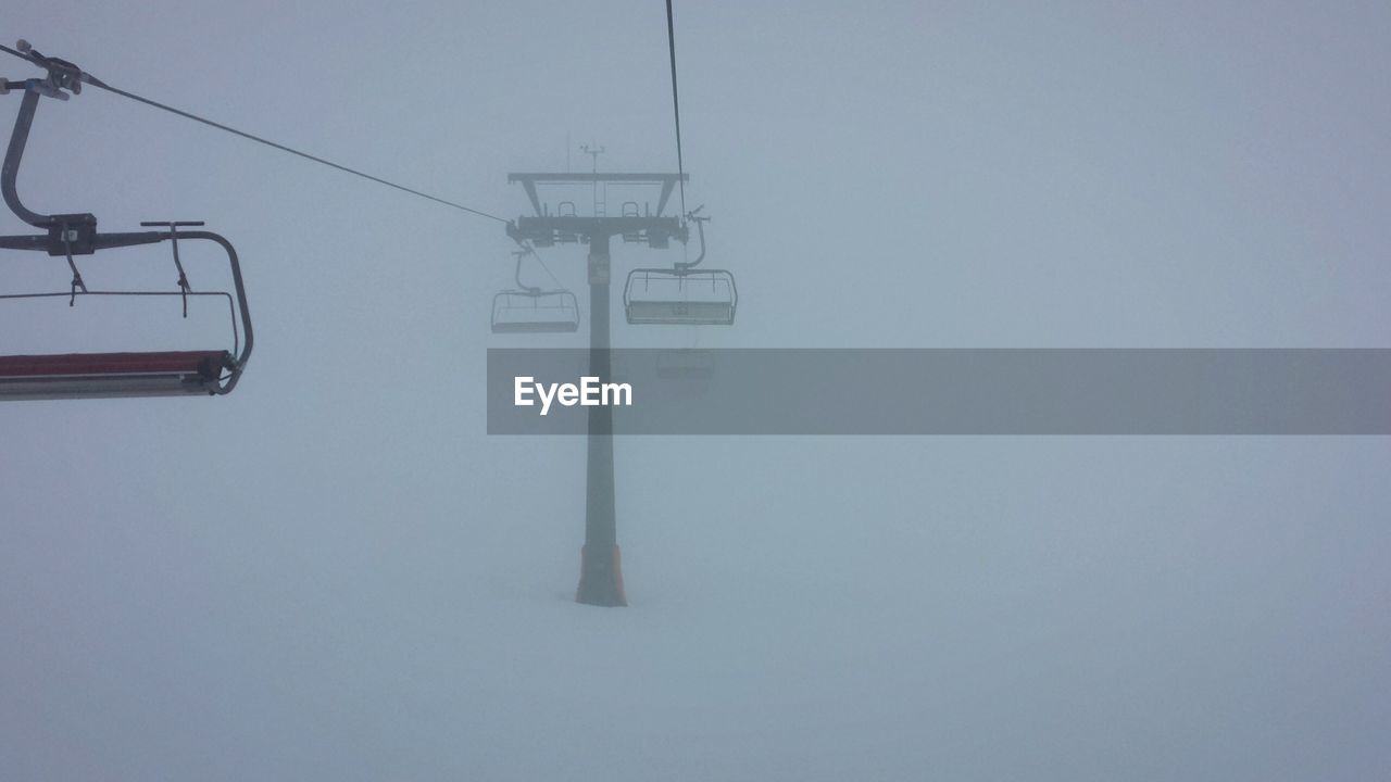 Ski lifts on snowcapped field in foggy weather